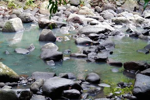 A stream of water is flowing between large rocks Stock Photos