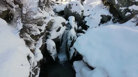 Stream with water flowing in mountain surrounded by snow in winter. alps 4k Stock Footage 148031301