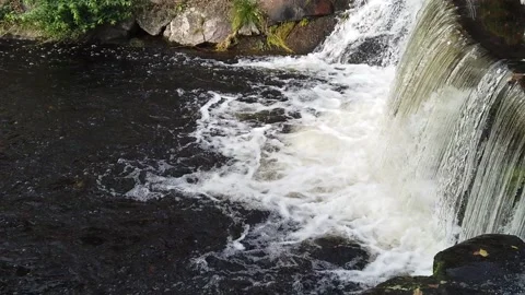 Stream of water flows along wall flowing into river Video stock 142603194