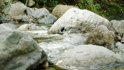 A stream of water flows between large rocks Stock Photos