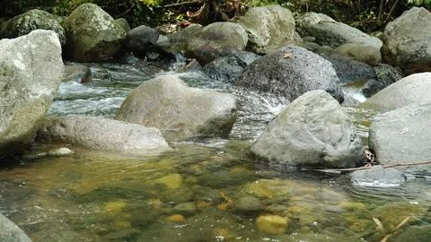 A stream of water flows between large rocks Stock Photos