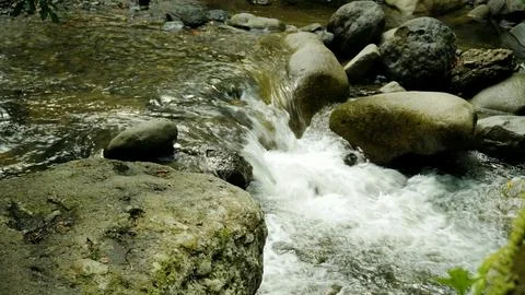 A stream of water flows between large rocks Stock Photos