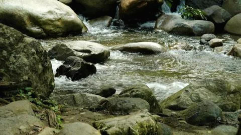 A stream of water flows between large rocks Stock Photos