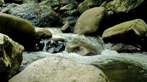 A stream of water flows between large rocks Stock Photos