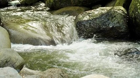 A stream of water flows between large rocks Stock Photos