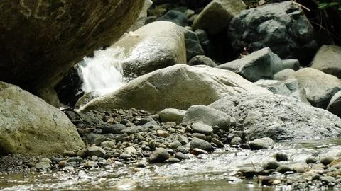A stream of water flows between large rocks Stock Photos