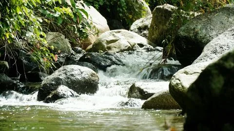 A stream of water flows between large rocks Stock Photos