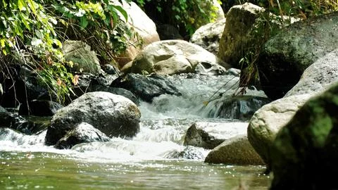 A stream of water flows between large rocks Stock Photos
