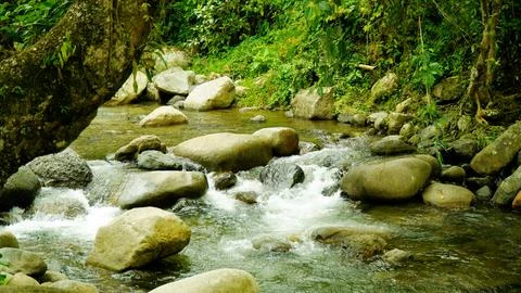 A stream of water flows between large rocks Stock Photos