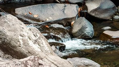 A stream of water flows between large rocks Stock Photos