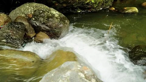 A stream of water flows between two large rocks Stock Photos