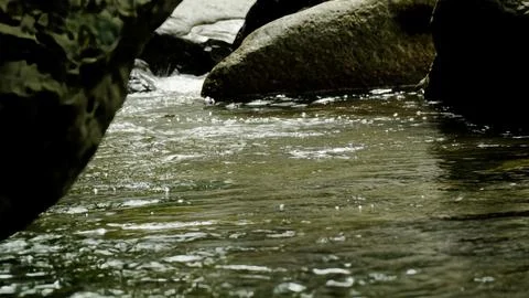 A stream of water flows between two large rocks Stock Photos