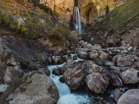 A stream of water flows down from a cave in the high rocks of the Caucasus... Stock Photos
