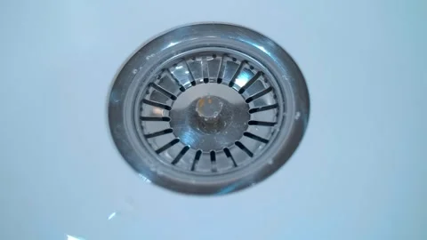 A stream of water flows into a shiny chrome drain in a white sink  Stock Footage 297770637