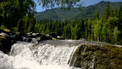 A stream of water flows through a large rock in a mountain river. Stock Footage 92670275