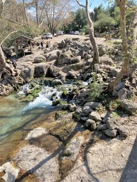 The stream of water flows through large stones and forms a small waterfall Stock Photos