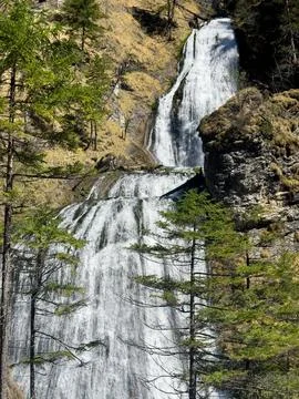 A stream of water in the form of a small waterfall flows among the mountains Stock Photos