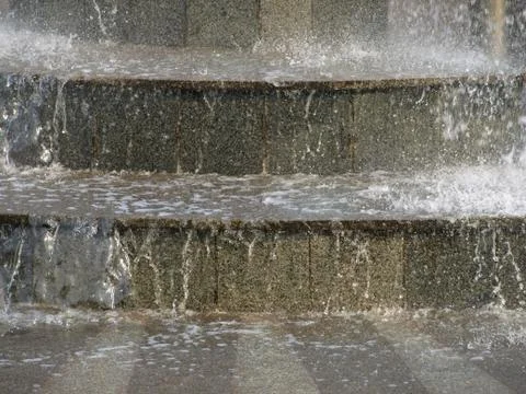 The stream of water on the granite steps.background. Stock Photos