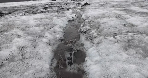 Stream water melt from ice flowing through Solheimajokull glacier covered by  Stock Footage 213601246