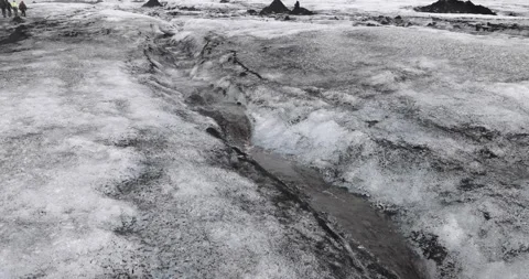 Stream water melt from ice flowing through Solheimajokull glacier covered by  Stock Footage 213601279