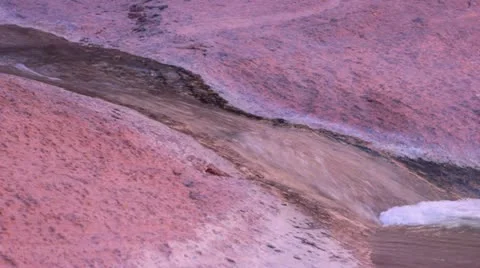 Stream of water over red rock into pond. Video stock 22360257