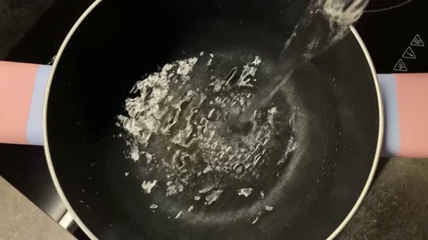 A stream of water is poured into an empty metal pan. A reflection of light plays 動画素材 150242692