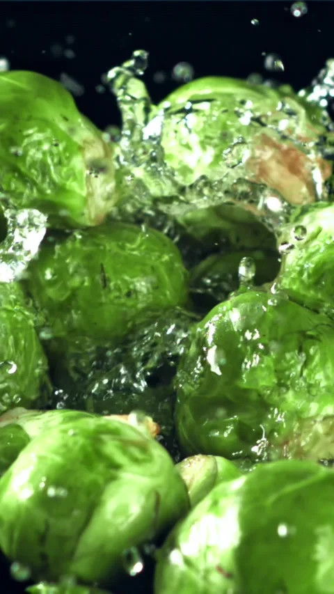 A stream of water pours into Brussels sprouts. Filmed on a high-speed camera at Stock Footage 335321875