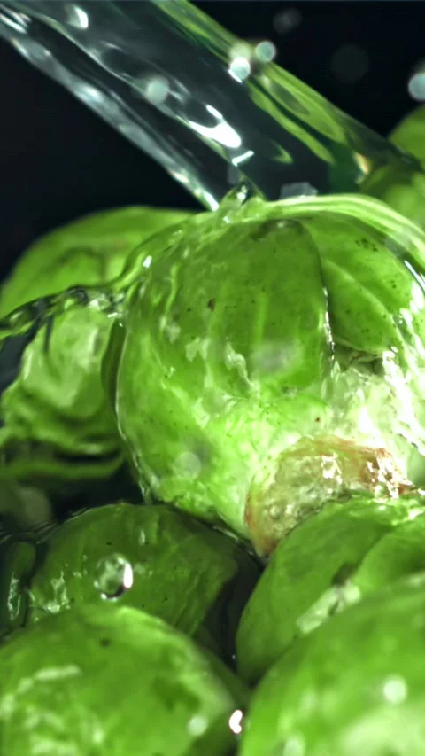 A stream of water pours into Brussels sprouts. Filmed on a high-speed camera at Stock Footage 335322102