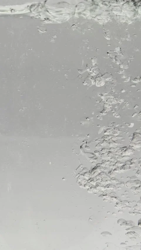 A stream of water pours into a glass container close-up.  water bubbles Video stock 309999992