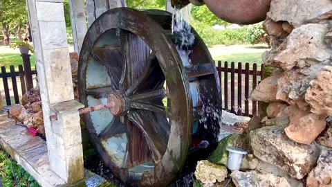 A stream of water pours from a jug onto a water wheel. Attractive fountain. Stock Footage 252171318