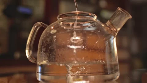A stream of water pours into a large clear teapot Stock Footage 264389245