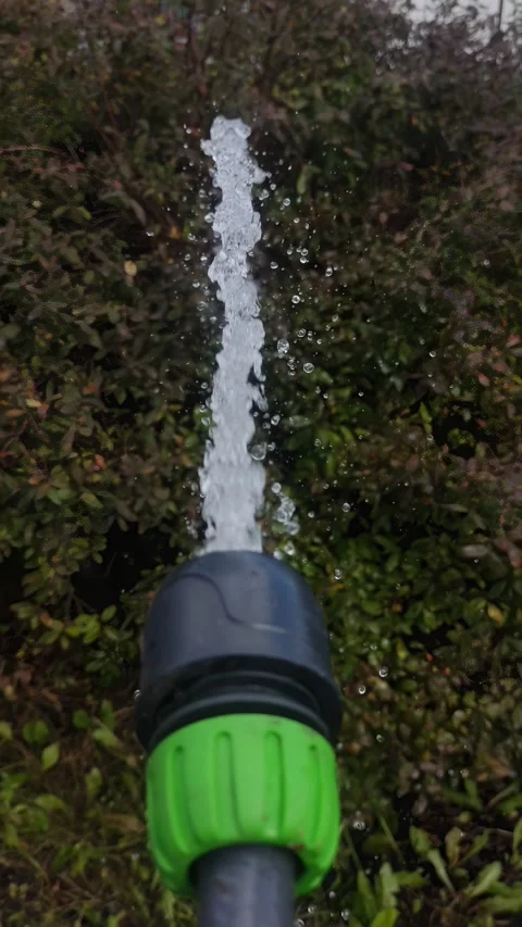 A stream of water sprays vertically from a garden hose. Stock Footage 344038432
