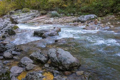 A stream of water in a stone riverbed, spewing noise and rumbling, making its Stock Photos