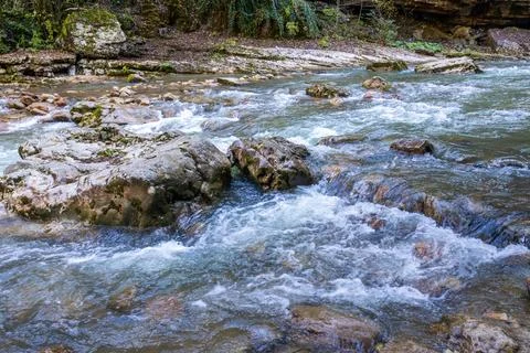 A stream of water in a stone riverbed, spewing noise and rumbling, making its Stock Photos