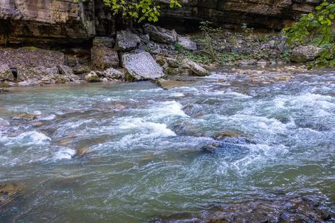 A stream of water in a stone riverbed, spewing noise and rumbling, making its Stock Photos