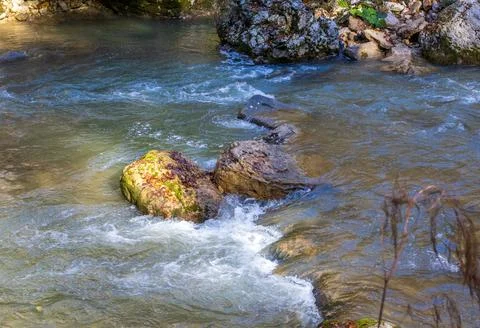 A stream of water in a stone riverbed, spewing noise and rumbling, making its Stock Photos