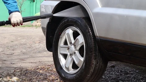 The stream of water washes the wheel of a car. Touchless car wash car at home. Vídeo Stock 128486283