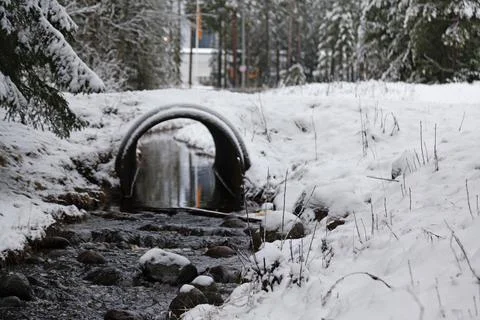 A stream in winter that flows under a road Stock Photos