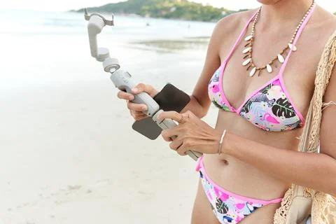 Streamer attaching a mobile to a tripod for a live broadcast from the beach Stock Photos