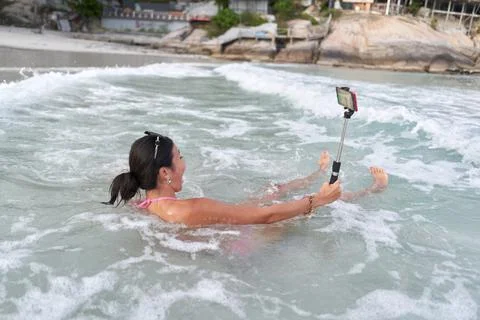 Streamer bathing in the sea while performing live with a mobile Stock Photos