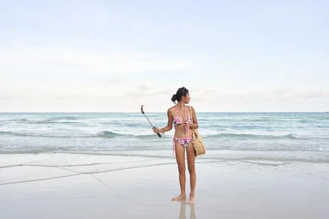 Streamer holding a mobile with a stick while looking distractedly at the sea Stock Photos