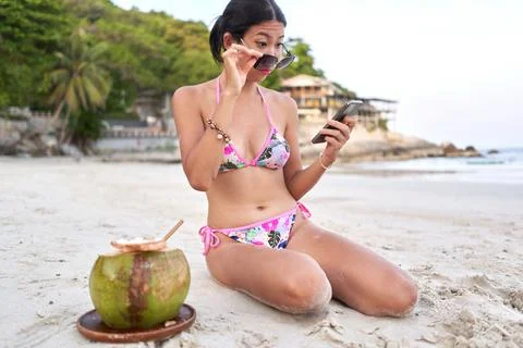 Streamer taking off his glasses to read his mobile screen on a beach Stock Photos