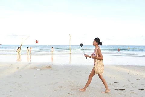 Streamer walking on a beach while doing a live stream using a mobile Stock Photos
