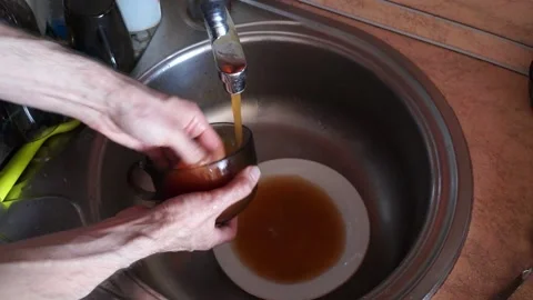 Streaming dirty rusty brown water in sink. Water stream going down the drain Stock Footage 157096977