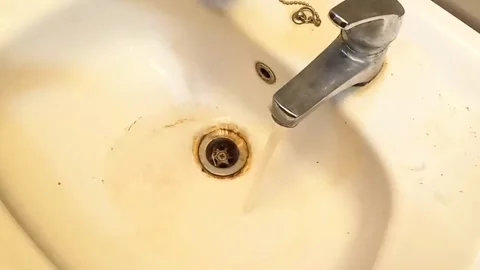 Streaming dirty rusty brown water in sink. Water stream going down the drain. Stock Footage 287159878