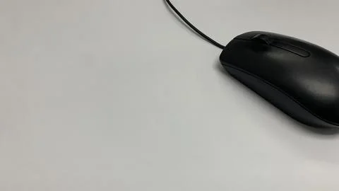 Streamline workflow with this simple black wired mouse on a white desk Stock Photos