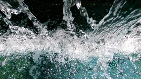 Streams of crystal clear water fall into the water creating splashes and bubbles Stock Footage 125443435