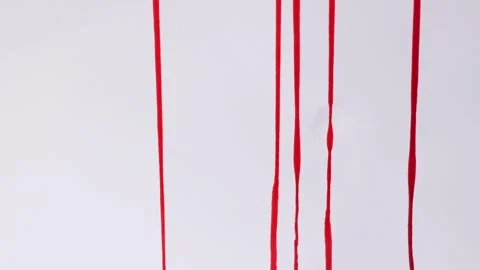 Streams of red paint or blood are pouring onto a white background. The concept Stock Footage 255198271
