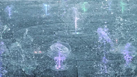 Streams spraying crystal water drops. Illuminated colorful droplets. 库存影片 245743689