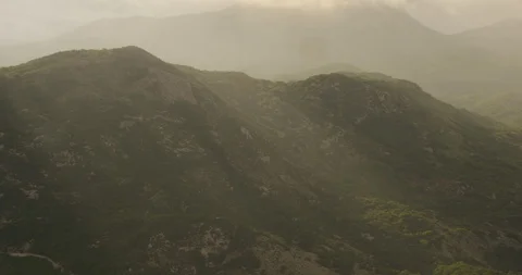 Streams of sunlight pouring through overcast, cloudy sky onto green mountains, Stock Footage 115057035